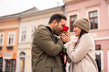 A happy mid adult Caucasian man and woman stroll down a city street on Valentine’s Day.