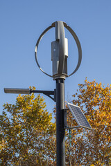 Vertical-axis wind turbine with solar panel under clear blue sky