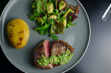 Medium rare beef steak with homemade Argentian style chimichurri, fondant potato and avocado salad