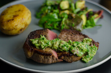 Medium rare beef steak with homemade Argentian style chimichurri, fondant potato and avocado salad