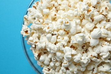 Delicious popcorn in a bowl on a colored background