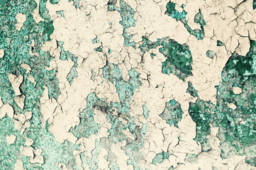Fototapeta premium Texture background - peeling paint on the old rough concrete surface, yellow and green peeling paint texture with cracks and fissures