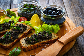 Tasty sandwiches with tapenade on wooden table	