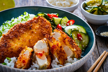 Tonkatsu - crispy Japanese pork chop with white rice and fresh vegetables on wooden table	
