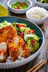 Tonkatsu - crispy Japanese pork chop with white rice and fresh vegetables on wooden table	
