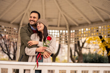 Mid adult Caucasian man and woman enjoying a heartfelt moment in a pavilion. The man surprises his...