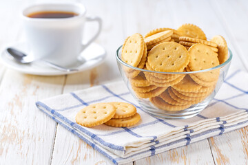 Salted crackers round shapes and coffee on a light kitchen table, selective focus.