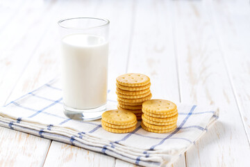 Saltine round crackers and milk on a white table, close up.