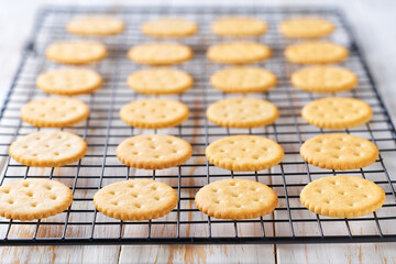 Wheat round crackers in a black wire rack on a white table, close up.