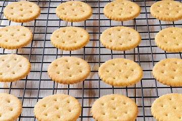 Wheat round crackers in a black wire rack on a white table, close up.