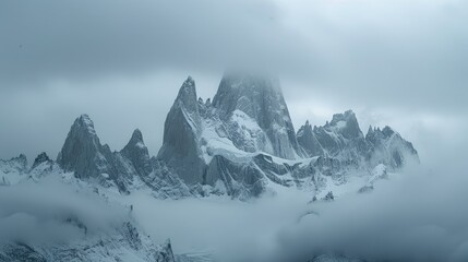 Obraz premium Majestic snow-capped mountains shrouded in clouds, evoking a sense of mystery and grandeur.