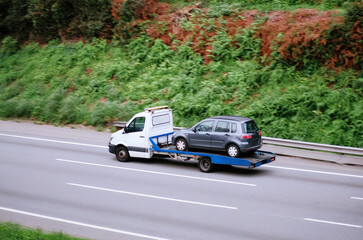 Tow Truck Transporting Minivan On Flatbed for Roadside Assistance