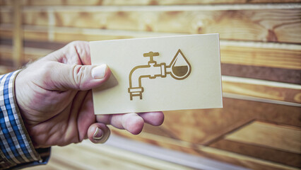 A hand holds a card with a gold-toned faucet icon, symbolizing water conservation.Close-up of a card displaying a water faucet graphic, highlighting the concept of responsible water use.
