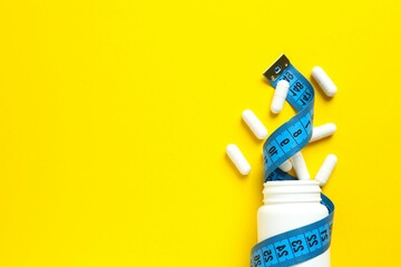 Jar of weight loss pills and measuring tape on color background, flat lay. Space for text