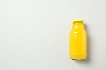 Bottle of freshly squeezed orange juice with citrus fruits on a gray background