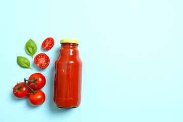 Tomato juice in a glass bottle and fresh tomatoes on color background