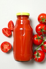 Tomato juice in a glass bottle and fresh tomatoes on gray background