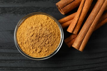 Cinnamon sticks and cinnamon powder in a plate on a wooden background