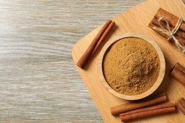 Cinnamon sticks and cinnamon powder in a plate on a wooden background