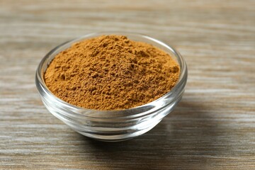 Cinnamon powder in a plate on a wooden background