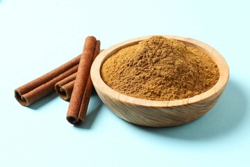 Cinnamon sticks and cinnamon powder in a plate on a color background