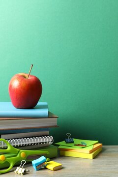 Back to school. Close-up of colorful stationery, textbooks, red apple on green chalkboard