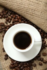 Cup of coffee and coffee beans on burlap