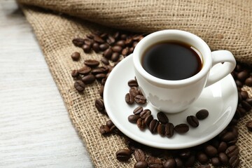 Cup of coffee and coffee beans on burlap