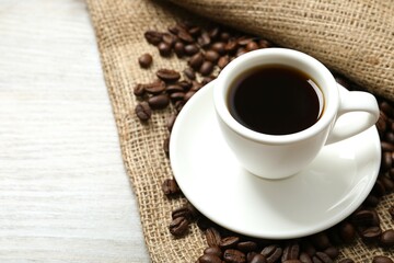 Cup of coffee and coffee beans on burlap