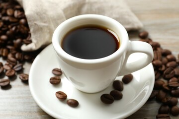 Cup of coffee and coffee beans on wooden background