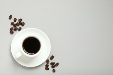 Cup of coffee and coffee beans on gray background