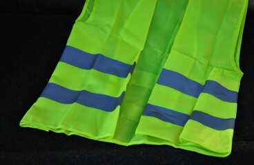 yellow safety vest with reflective stripes on a dark background.