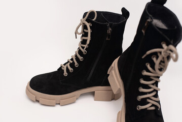 Pair of trendy black suede boots, featuring beige soles and laces, ideal for fashion enthusiasts...