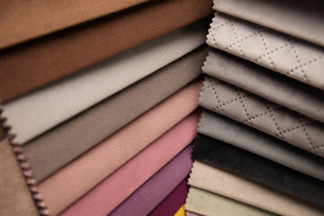 A neatly arranged stack of different textiles showcasing various colors, textures, and surface...
