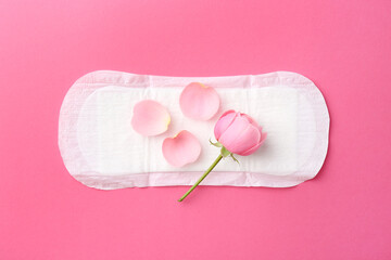 Menstrual pad with flower on pink background, top view