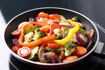 Frying pan with mix of vegetables and mushrooms on cooktop, closeup