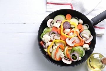 Frying pan with mix of vegetables and mushrooms on white wooden table, top view. Space for text