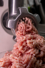 Close-up of minced meat falling out of a meat grinder. Making fresh minced meat. Food concept