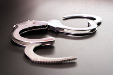Pair of handcuffs used by law enforcement to arrest criminals on a black background. Justice or...