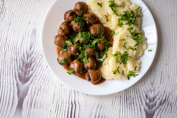 Swedish Meatballs with Gravy Sauce on a plate with mashed potatoes on a wooden background