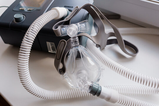 CPAP machine and mask on white surface for sleep apnea therapy