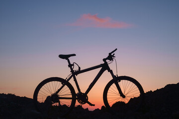 Obraz premium The silhouette of a bike on the sunset sky background