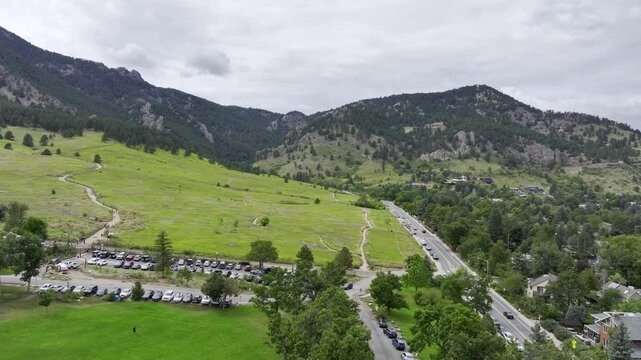 Flatirons in Boulder Colorado Aerial Drone footage. Dramatic cloudy day in September. Mountainous landscape and hiking trails visible. Rocky Mountain foothills and Boulder downtown nearby.