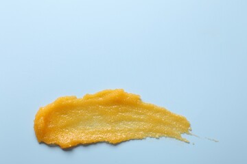 Smear of body scrub on light blue background, top view. Space for text