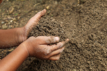 Close up of a little boy's hands playing with dirt or sand. child playing outdoors.