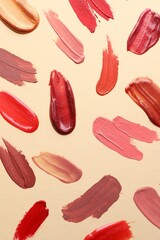 Samples of different lip products on beige background, top view