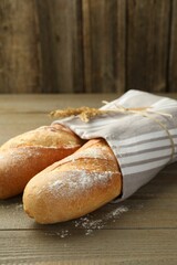 Freshly baked baguettes on wooden table, closeup