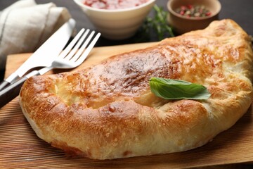 Delicious fresh calzone pizza served on wooden table, closeup