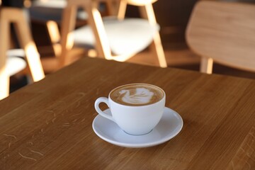 Cup of aromatic coffee on wooden table in cafe