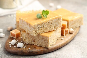 Delicious puffed rice bars, candies and mint on gray textured table, closeup